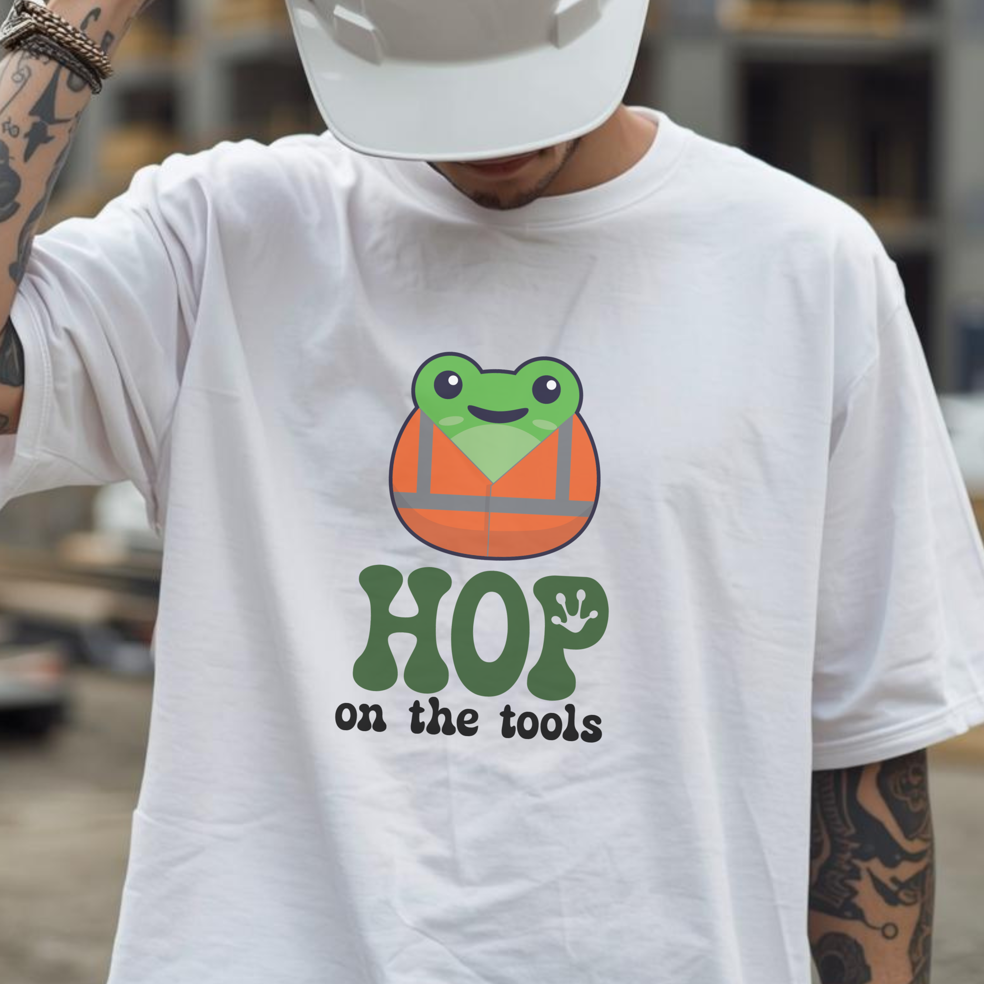 Person wearing a white t-shirt with a frog graphic and text 'Hop on the tools' in an urban setting.